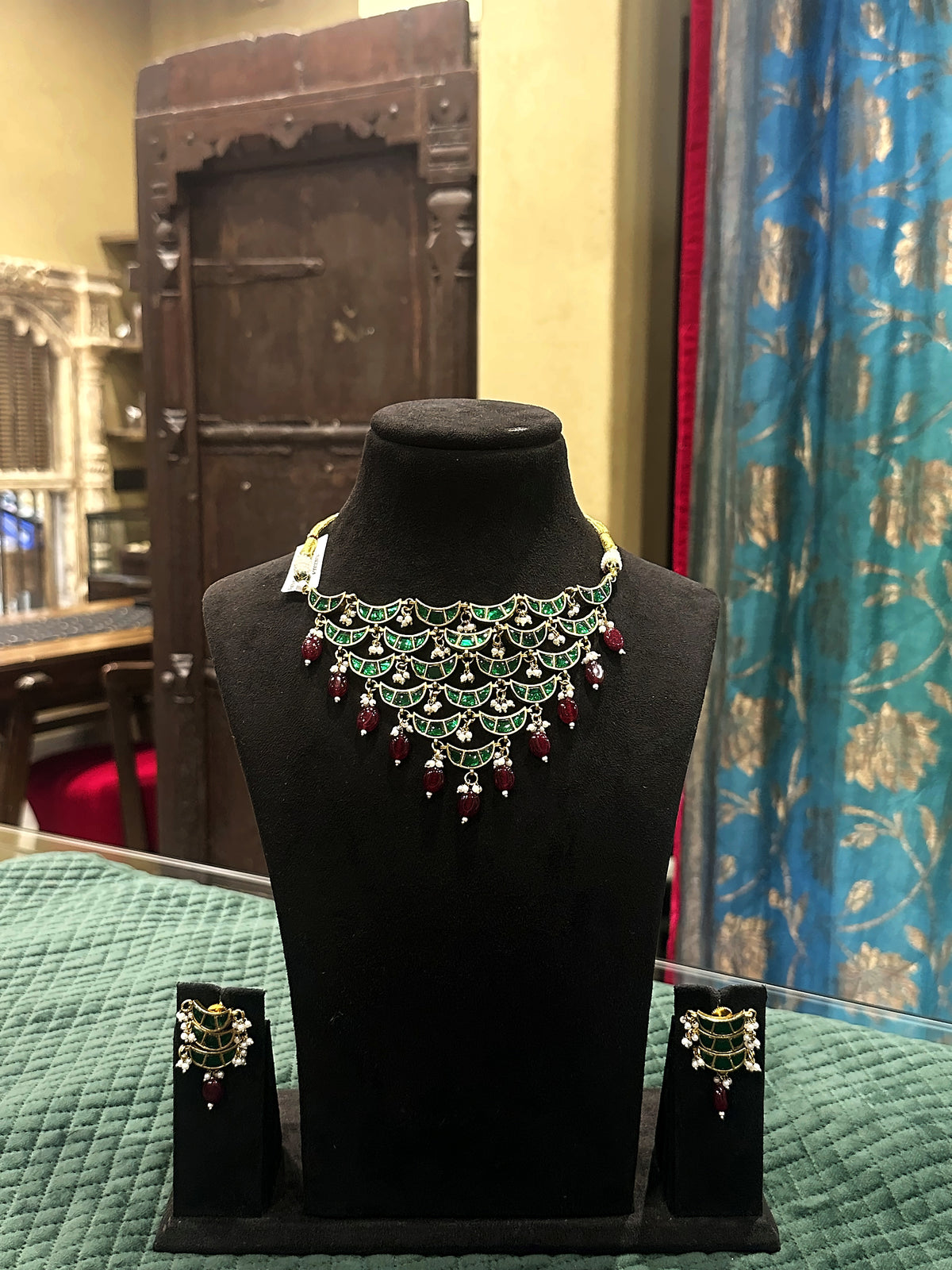 Jadtar moti festive necklace set with green stones, ruby drops and matching earrings on black velvet bust – Studio Gulabi 926HAI079